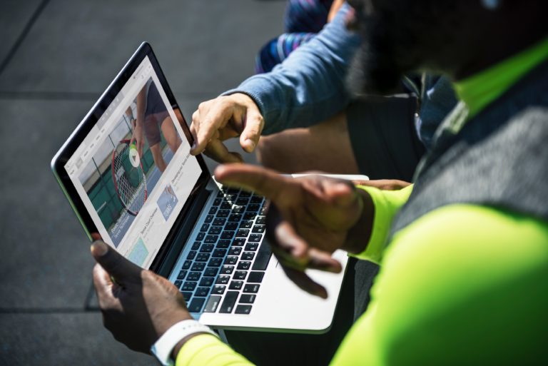 Two people work together on a an open laptop