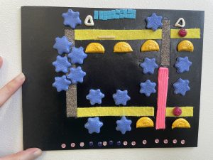 A tactile map of the Beyond Vision route through Warley Woods, made from textured air-dry clay pieces for trees, felt and sandpaper pathways, and a plastic diamante street road.
